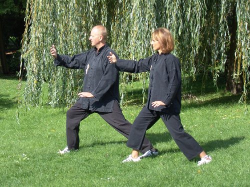 Ein Mann und eine Frau praktizieren Tai Chi im Park.